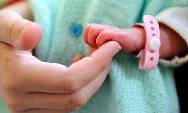 Newborn baby holds mother's fingers